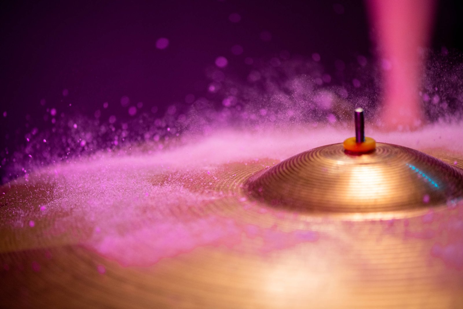 Tiny waterdrops hitting cymbal of golden color against purple background